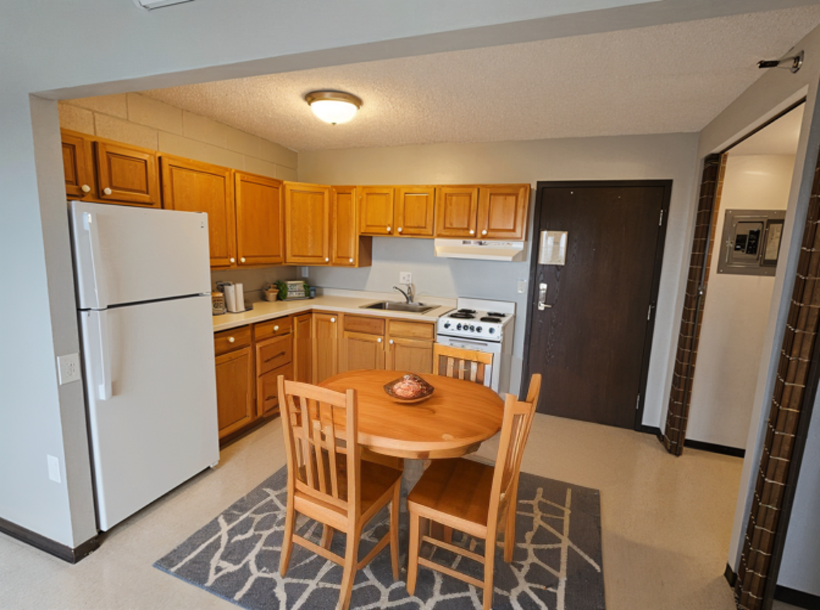 MetroView apartment kitchen and dining area with wood cabinets and a round dining table