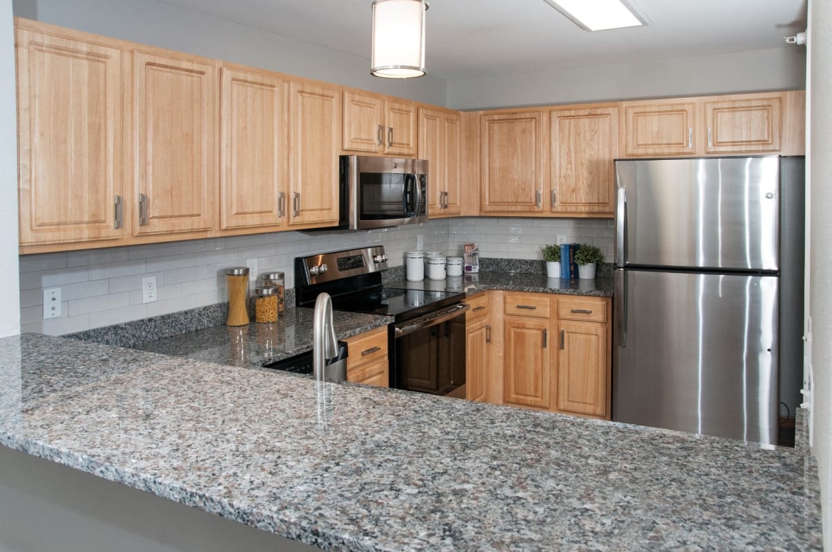 Apartment kitchen with wood cabinets, granite countertops, and stainless steel appliances