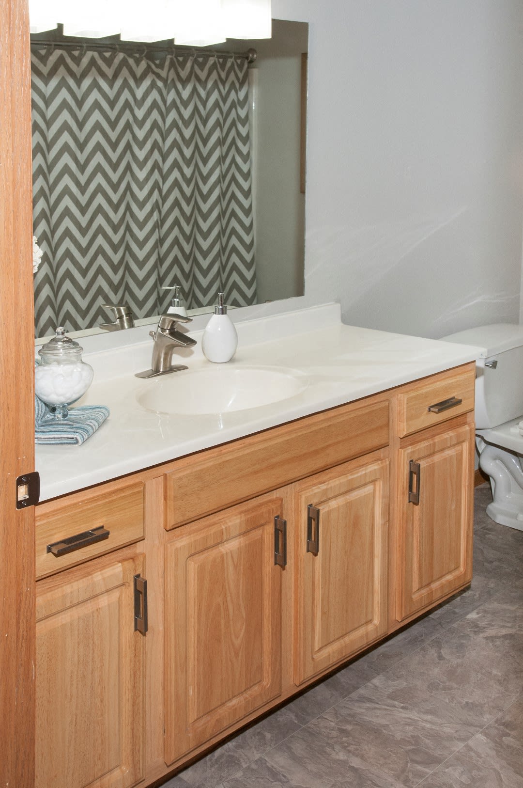Apartment bathroom vanity with wood cabinets and counter space