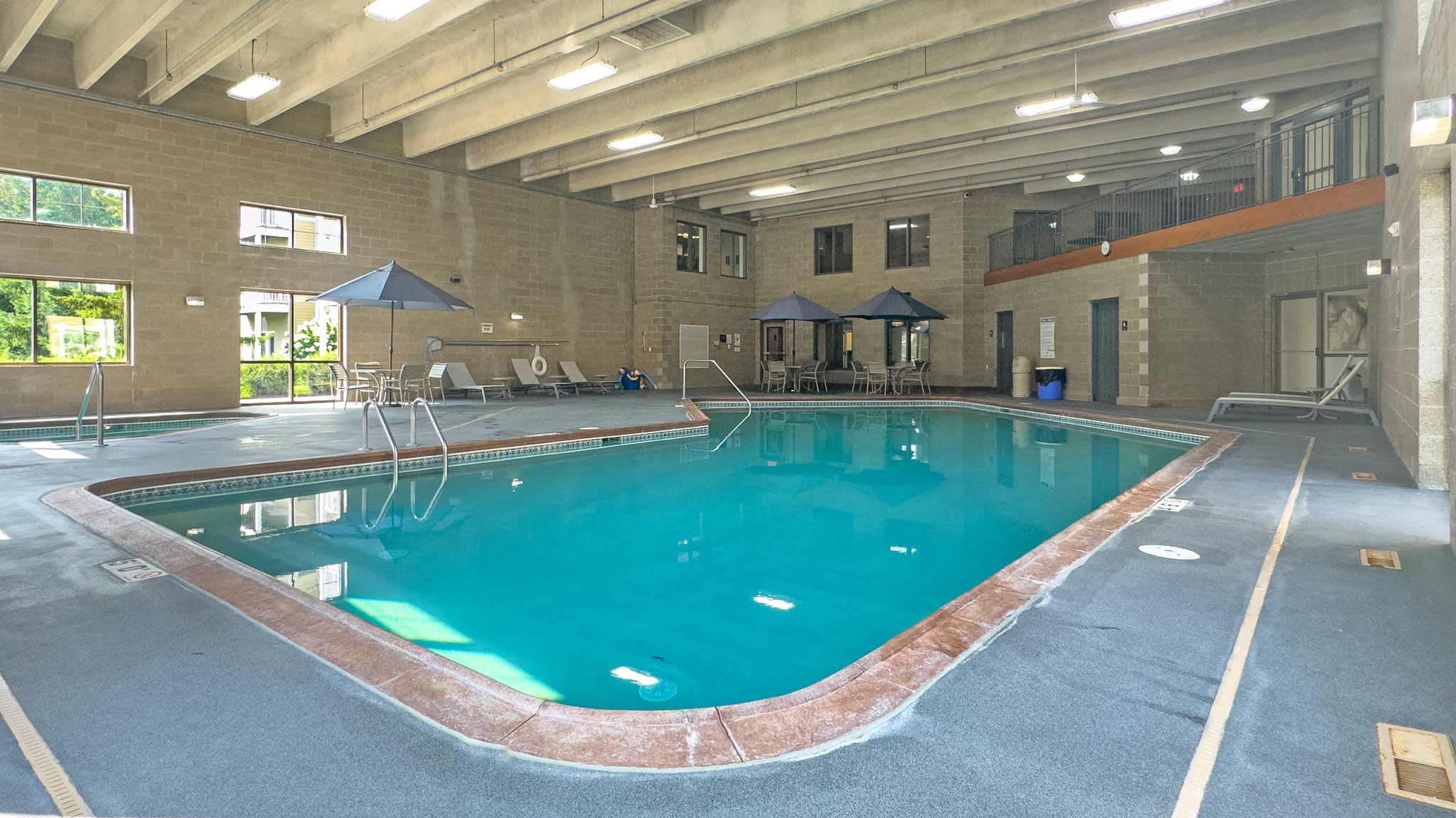 Indoor swimming pool with a surrounding deck and tables