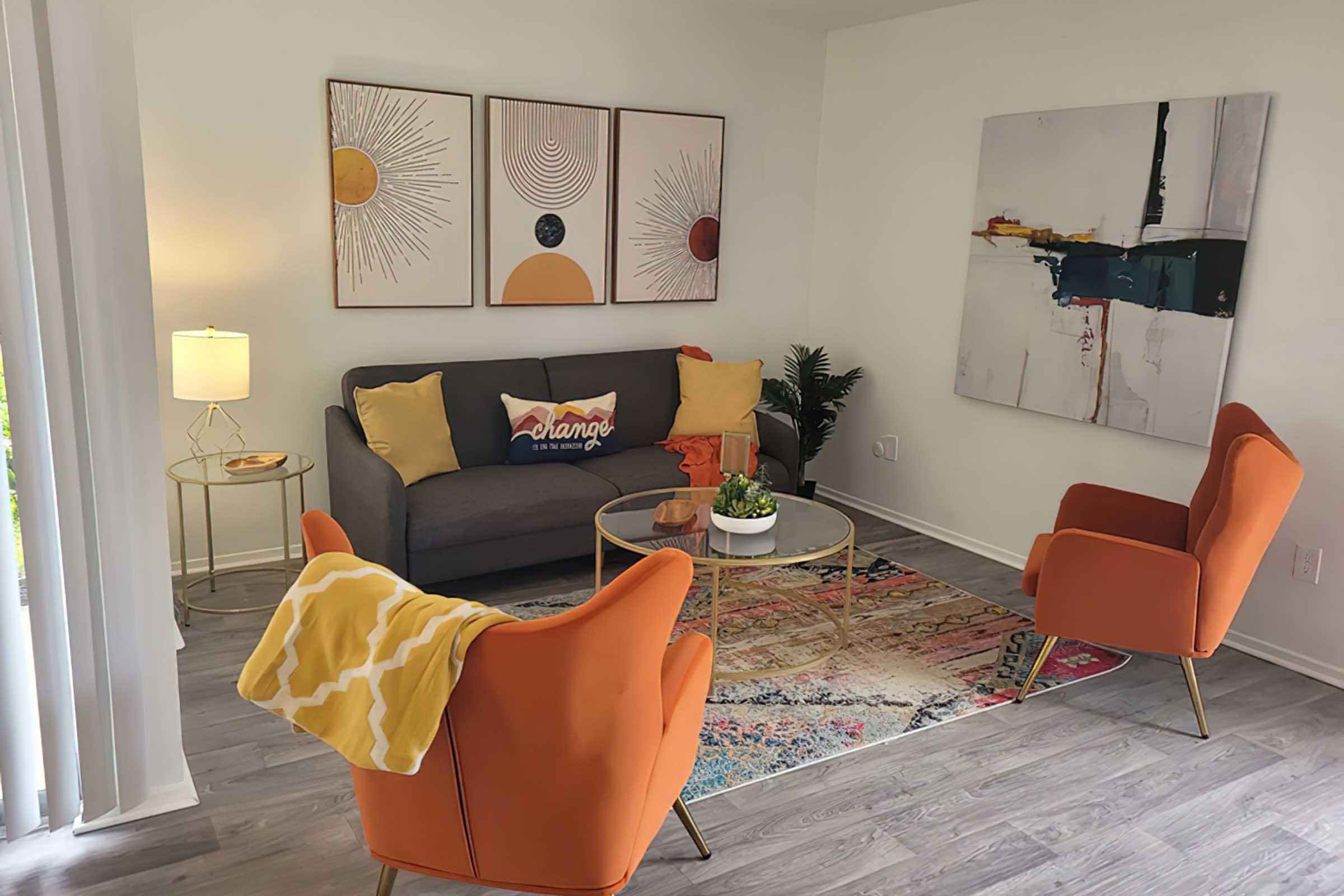 Furnished District at Midtown model living room with orange accent chairs.