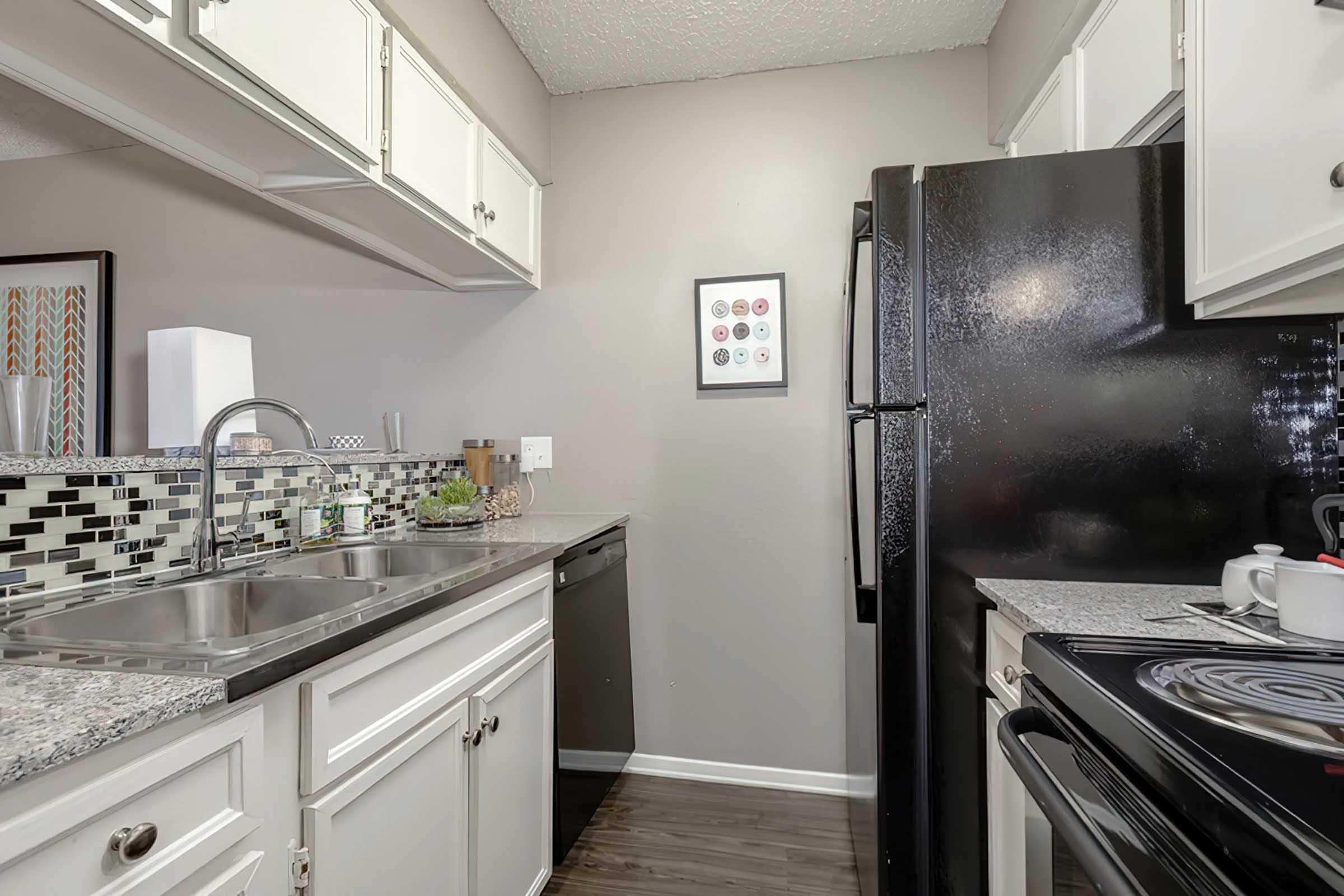 District at Midtown model kitchen with white cabinets and black appliances.