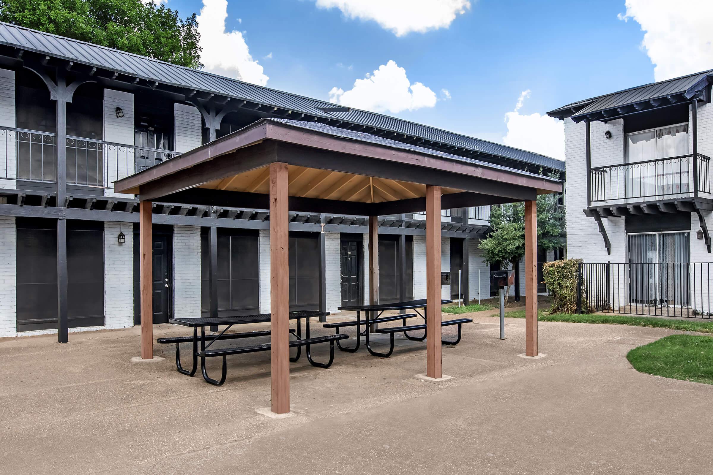 Covered picnic tables beside Maravilla apartment buildings.
