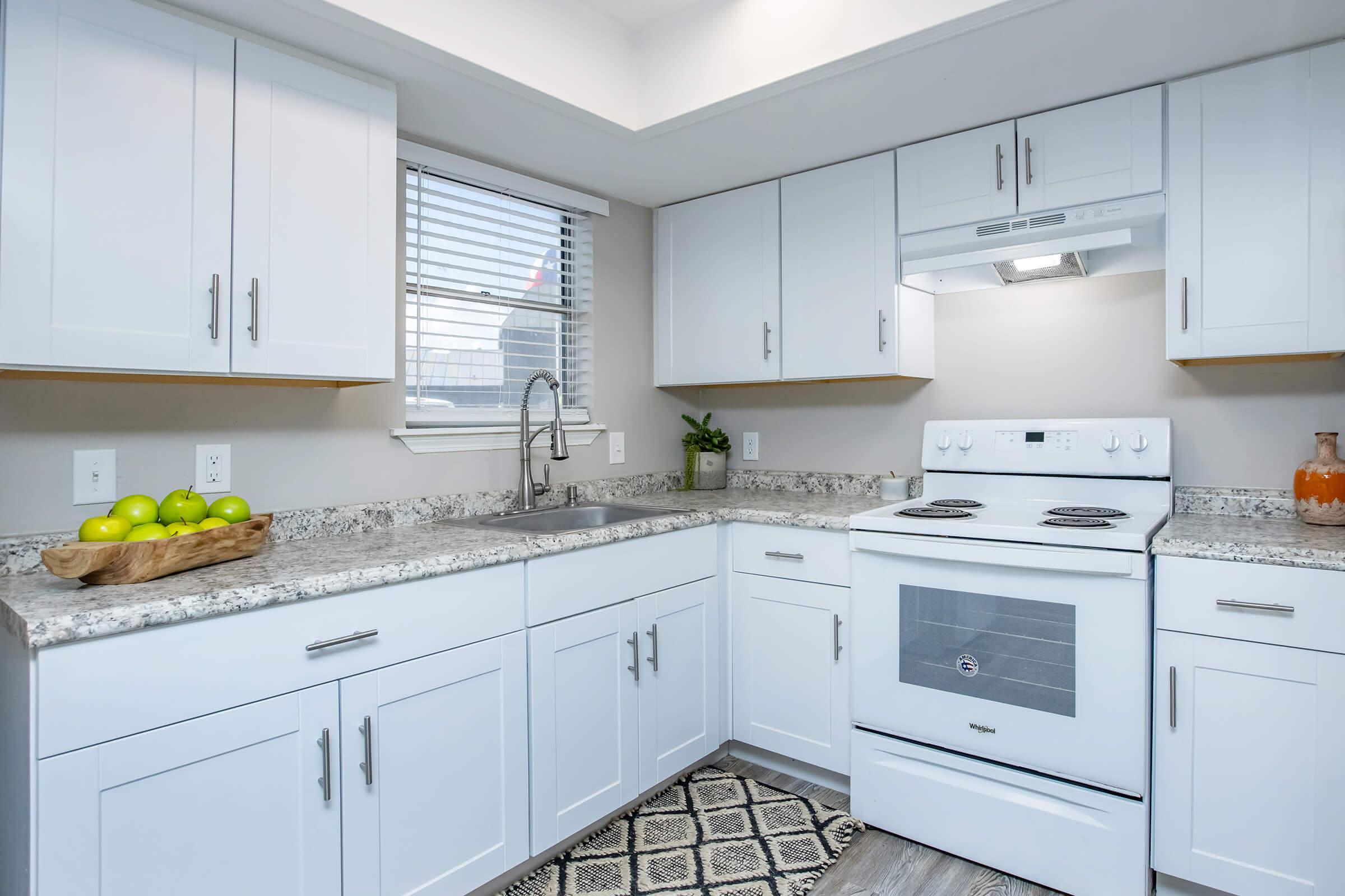 Maravilla model kitchen with white cabinets and granite counters.