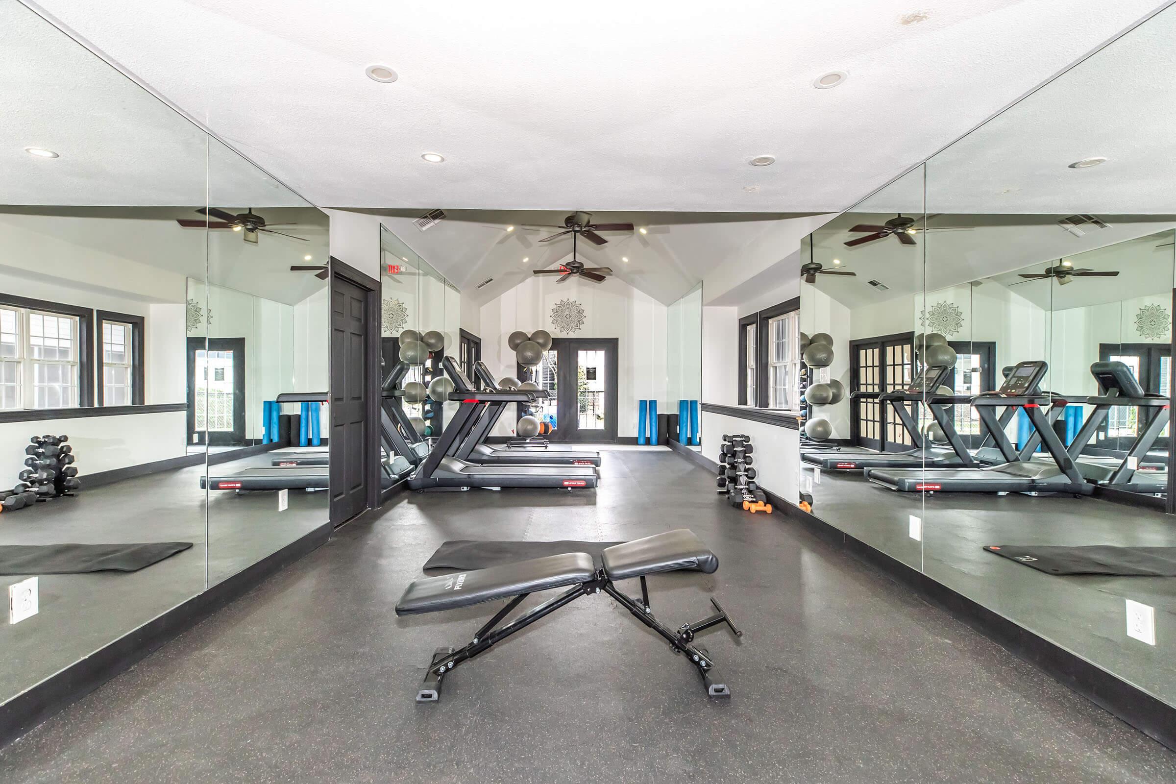 Fitness center with a weight bench, mirrors, and cardio equipment