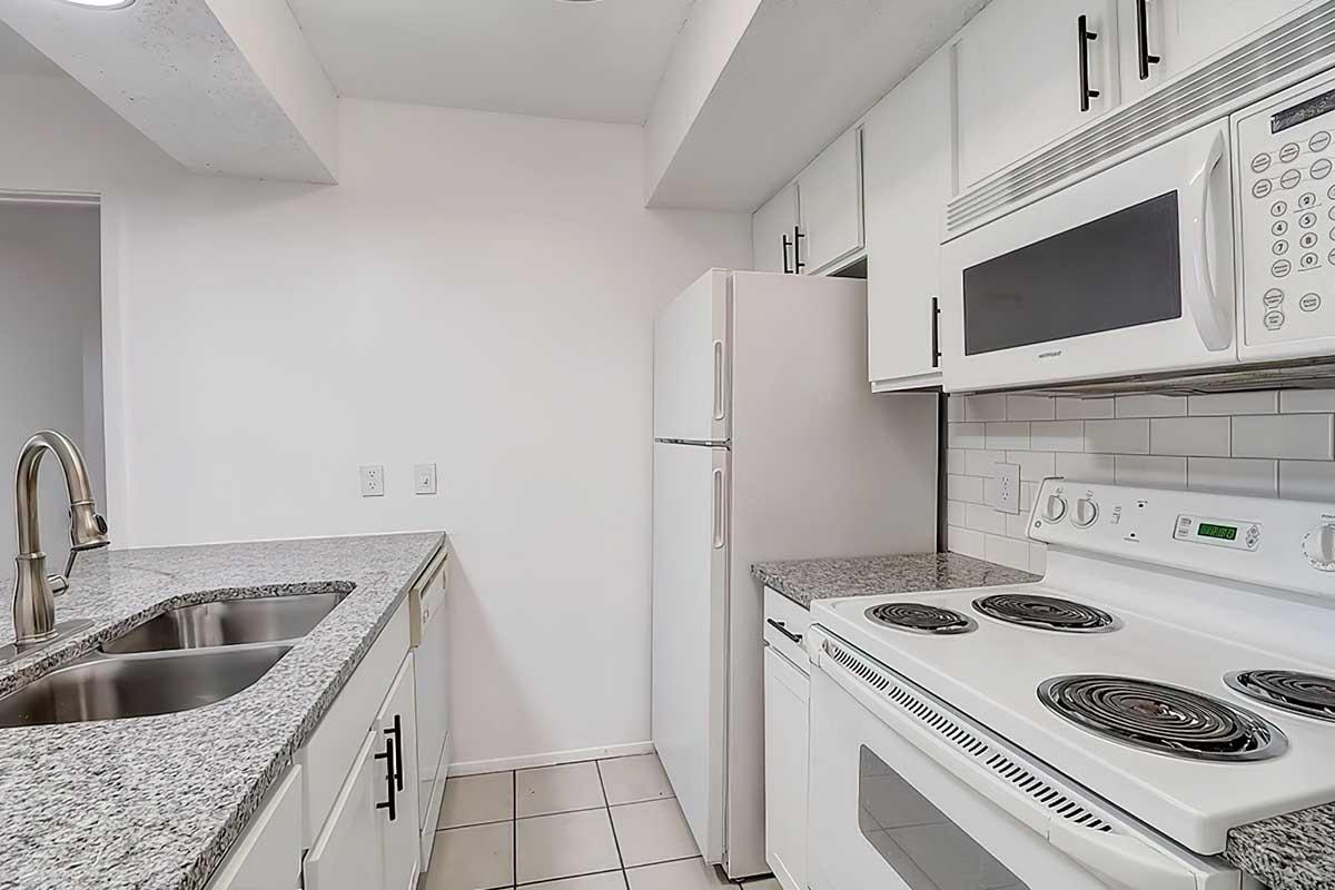 Apartment kitchen with white appliances, cabinets, and granite countertops