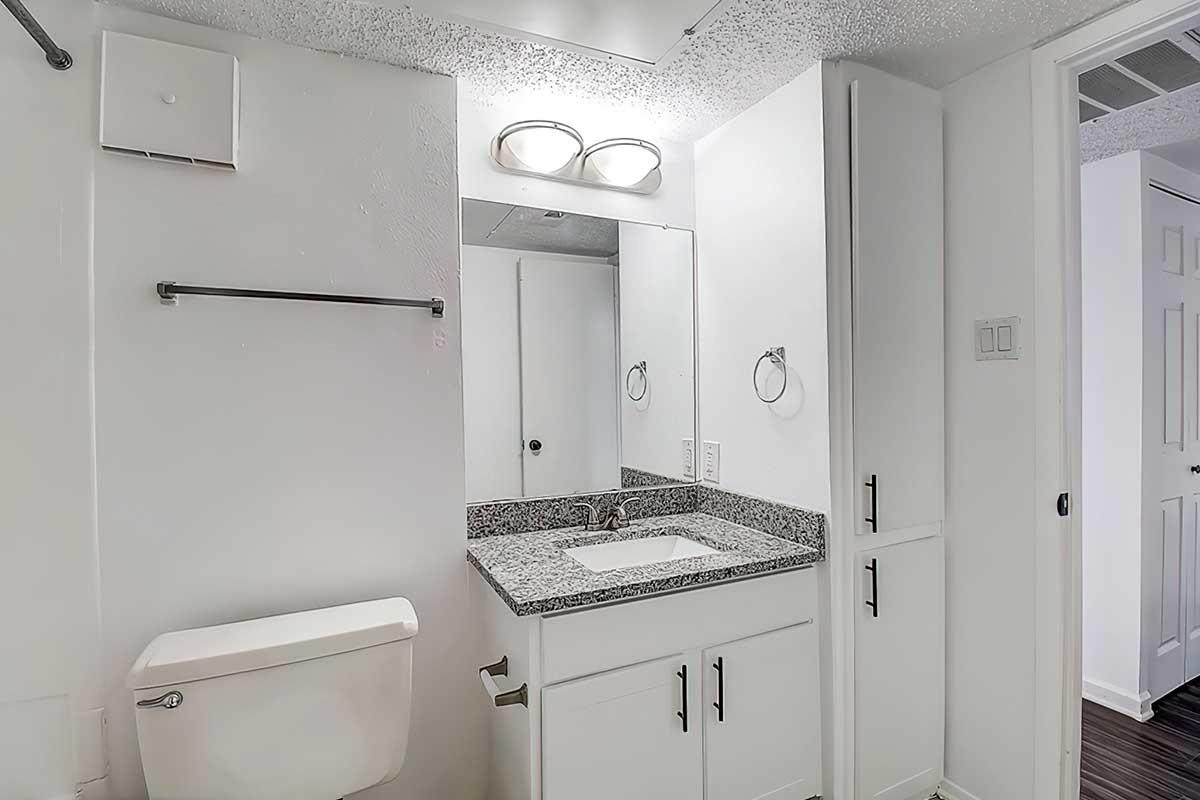 Apartment bathroom with a granite vanity and white cabinetry