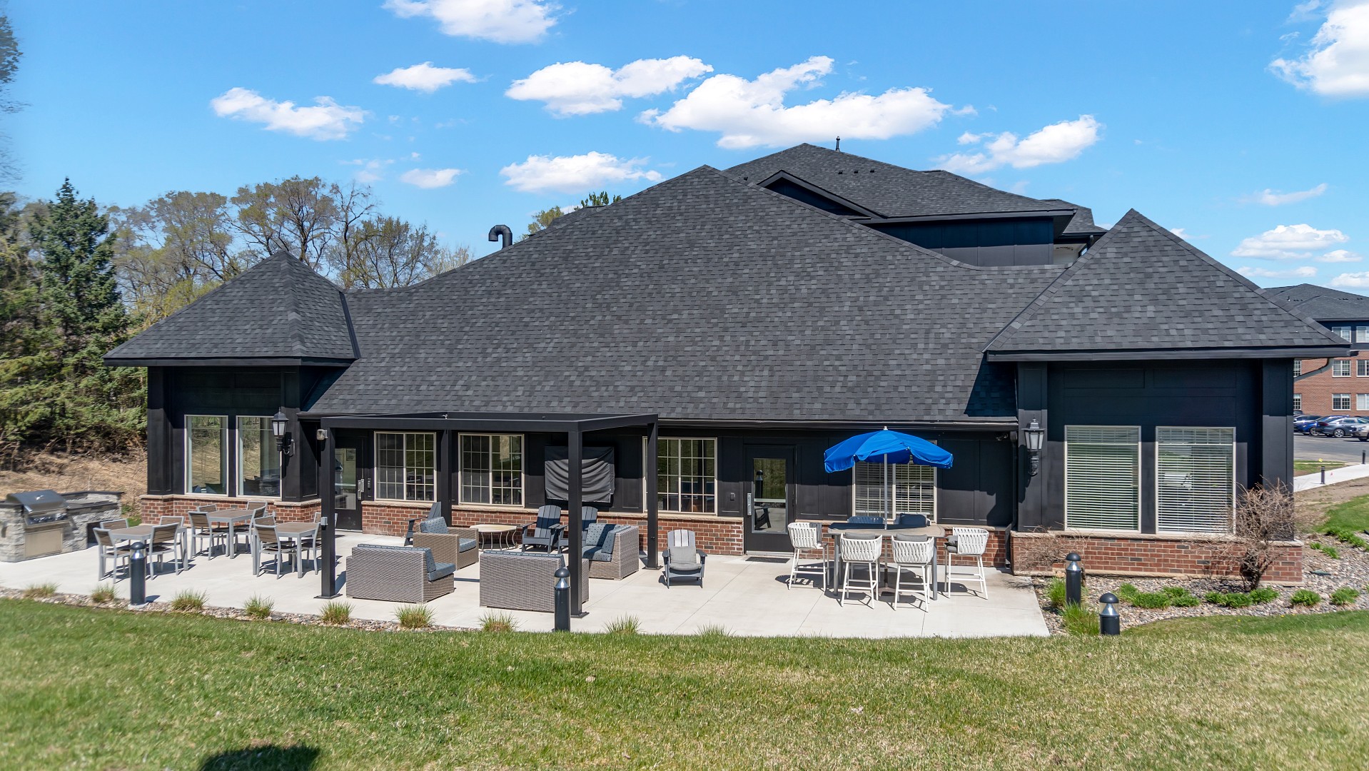 Waterstone Place clubhouse exterior and patio with dining tables and umbrellas.