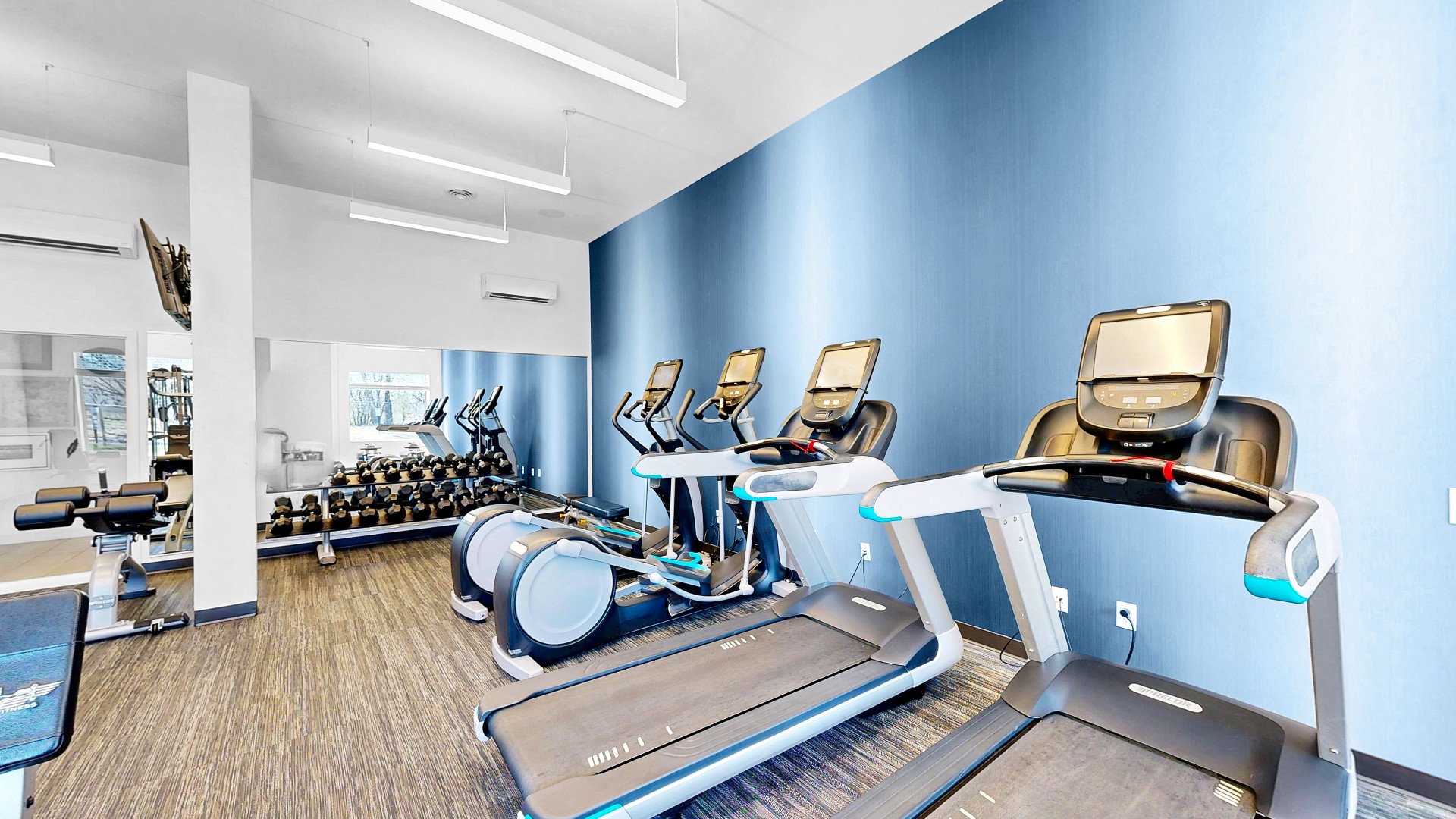Waterstone Place fitness center with treadmills, an elliptical, and a dumbbell rack.